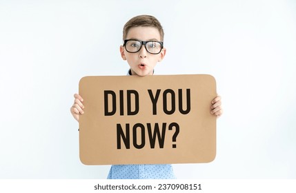 Close-up Child boy 9 years old holds a blank sheet of paper in his hands, a mockup of an empty brown board for shouting a text rule or a word of protest. Text Did you now? - Powered by Shutterstock