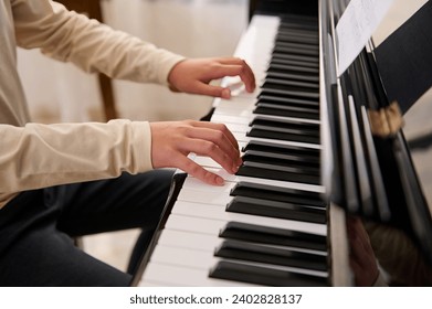 Close-up of a child boy touching piano keys with fingers, performs a musical composition while playing grand piano. Lesson of music.