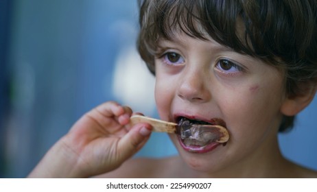 Closeup child face finishing icecream dessert. Messy young boy mouth covered in chocolate enjoying ice cream - Shutterstock ID 2254990207