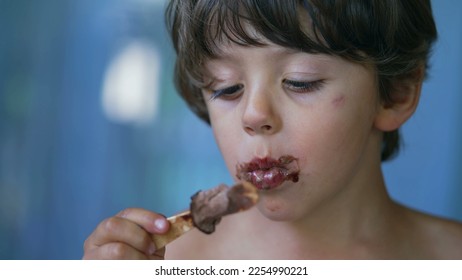 Closeup child face finishing icecream dessert. Messy young boy mouth covered in chocolate enjoying ice cream - Shutterstock ID 2254990221