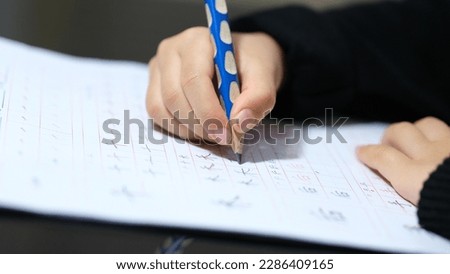 Closeup of child hands holding a pencil practicing writing. Asian school child. Chinese child homework. 