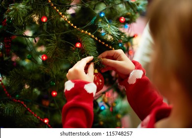 Close-up of child hanging decorative toy ball on Christmas tree branch - Powered by Shutterstock