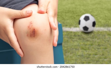 Close-up Of A Child Male Soccer Player Suffering From Knee Injury On The Field