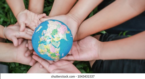 Closeup Children Hands Holding Earth ( Blur ) Over Green Grass Background. World Harmony Green Peace Environment Spring And Earth Day Together, Sustain Ecology, Climate Change Concept Panorama Banner