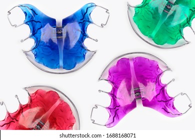 Close-up of children's orthodontic appliances in bright, fun colours on a white table. Concept of oral health in childhood.
