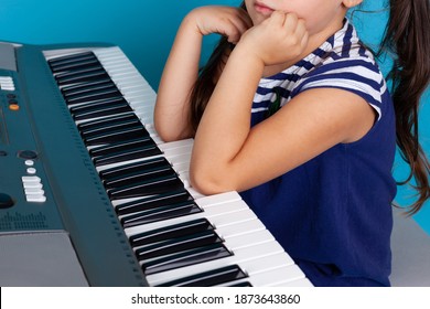 Close-up Of A Child's Elbows Pressing Or Playing Music On The Piano Keys, Limited Options, Isolated On A Blue Background.