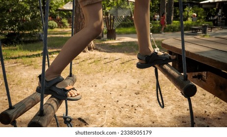 Closeup of childs feet walking over wobbly rope bridge in park. Active childhood, healthy lifestyle, kids playing outdoors, children in nature - Powered by Shutterstock