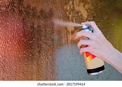 Close-up Of A Child's Hand Drawing Graffiti With Spray Can On The Wall. Side View Of An Artist Painting With Aerosol Spray On The Wall.