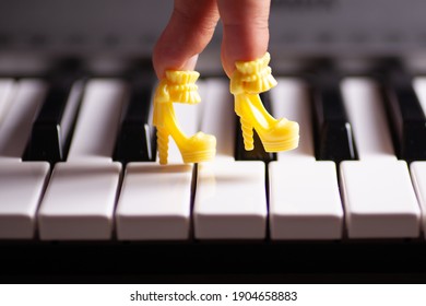 close-up a child's hand with fingers stuck in a toy yellow high-heeled doll's shoes steps on the piano keys