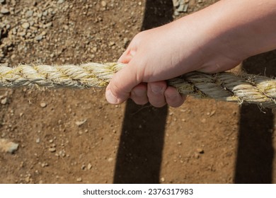 Close-up of a child's hand holding a rope on the playground. - Powered by Shutterstock