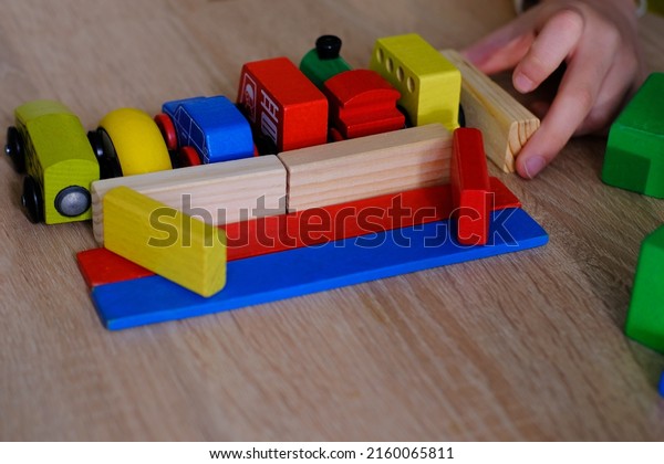 close-up of child\'s hands holding colored wooden\
cubes, dominoes, child 7-9 years old builds houses, rolls cars,\
concept of construction game, development of creativity, fine motor\
skills, patience