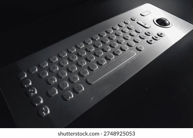 A close-up of a child's hands using an adaptive computer keyboard with large keys and a trackball. Concept: rehabilitation tools and educational support for children with disabilities