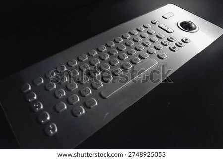 A close-up of a child's hands using an adaptive computer keyboard with large keys and a trackball. Concept: rehabilitation tools and educational support for children with disabilities