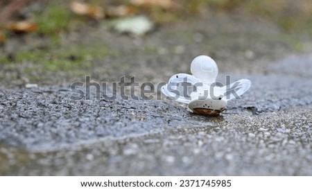 Close-up of a child's pacifier lying isolated on the asphalt on a dreary day, which makes you feel sad when you look at it