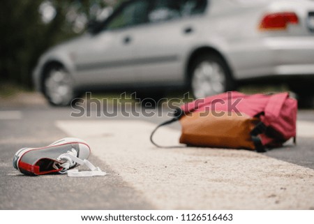 Close-up of child's shoe and knapsack on a pedestrian crossing after a collision with a car