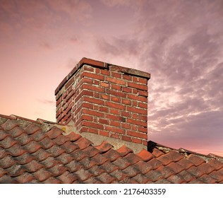 Closeup Of A Chimney On An Old Red Brick House With Copy Space Sky. Architectural Details Of An Antique Steel Roof On A Residential Building. Stone Exterior Design Of A Home Furnace Without Smoke