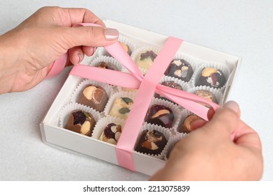 Closeup Of A Chocolate Box Present Being Wrapped. Woman Packing Home Made Candy In A Gift Box. 