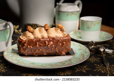 A Closeup Of Chocolate Nuts Cake Covered With Creamy Topping On A Plate