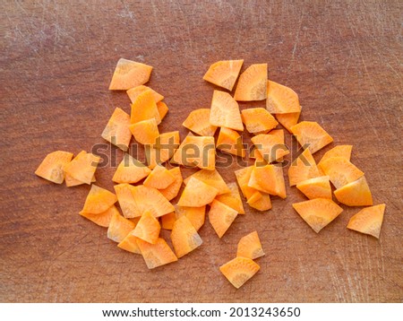 Closeup of chopped carrots on a wooden board. Paysanne cut.