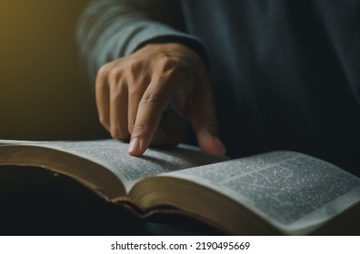 Close-up of Christian man's hands while reading the Bible outside.Sunday readings, Bible education. spirituality and religion concept. Reading a book. - Shutterstock ID 2190495669