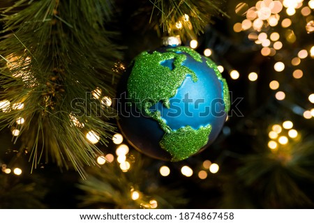 Close-up of Christmas bauble decoration ornament globe planet earth  on the background of the Christmas tree. Merry christmas and new year concept. Selective focus