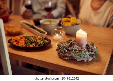 Close-up Of Christmas Candle On Dining Table With People In The Background.