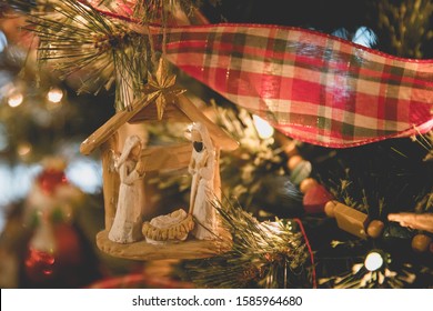 Closeup of Christmas Nativity Ornament with Joseph, Mary and Baby Jesus on Christmas tree with plaid ribbon and wooden beads  - Shutterstock ID 1585964680