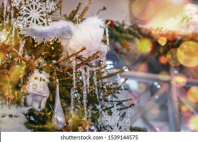 Closeup of Christmas and New Year tree with light, bokeh, snow flake. Holiday background. Christmas tree decorated with with icicles, toys, owls, garlands, close-up. Fir tree with piles of snow. Card.