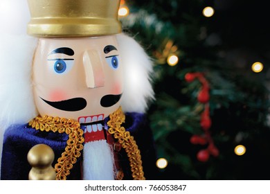 Closeup of Christmas nutcracker in front of a lit tree. Wooden soldier toy gift from the ballet. 