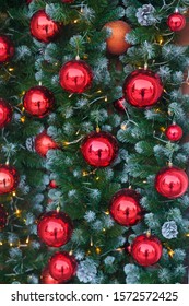Close-up of a Christmas tree decorated with red glass balls and light garlands. Lights and cones hang on the Christmas tree for the New Year.