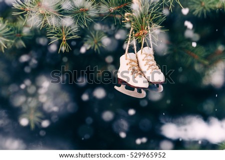Closeup christmas tree decoration small ice skates on the snowfall background