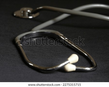Close-up of a chrome-plated stethoscope with a gray rubber hose on a black background.DCF 1.0