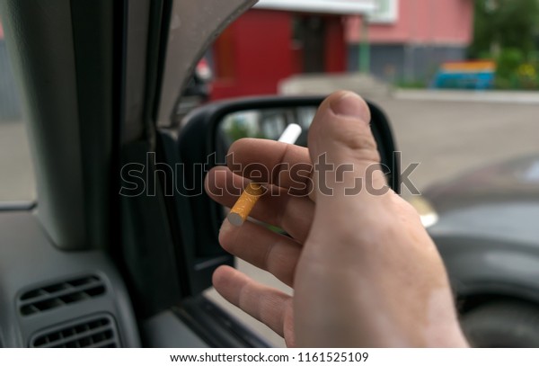 close-up of a cigarette in the\
hand of a man in the car, who watches the entrance door of the\
house