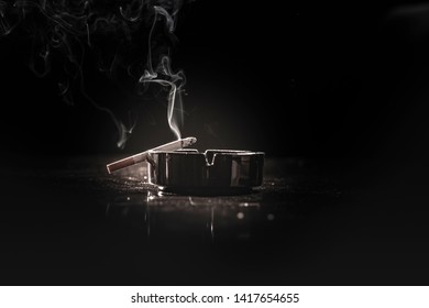 Closeup of cigarette on ashtray with a beautiful wisp of smoke 