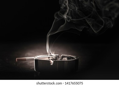 Closeup Of Cigarette On Ashtray With A Beautiful Wisp Of Smoke 