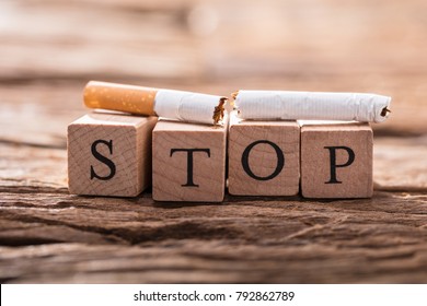 Close-up Of A Cigarette And Wooden Blocks Showing Stop Word On Desk