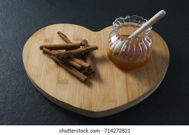 Close-up of cinnamon sticks and honey on heart shaped chopping board - Powered by Shutterstock