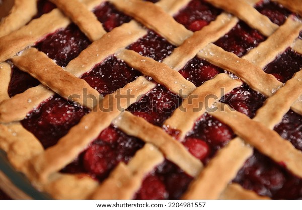 Close-up of a classic American\
cherry pie with crispy sweet pastry lattice. Homemade festive\
cherry cake with a flaky crust. Thanksgiving concept. Bakery\
products