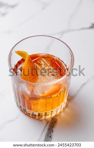 Close-up of a classic old fashioned cocktail garnished with a fresh orange twist on a marble surface