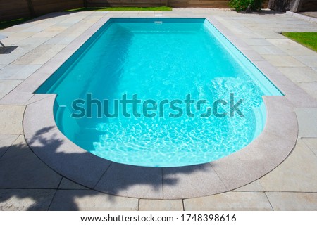 Closeup of a classic private swimmingpool in garden in the summer. with stairs