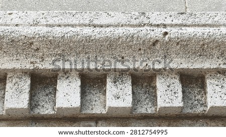 Close-up of a classical architectural stone molding, featuring a dentil course pattern. The weathered, rustic texture of the limestone highlights historical European craftsmanship, perfect for architecture, construction, and art history projects.