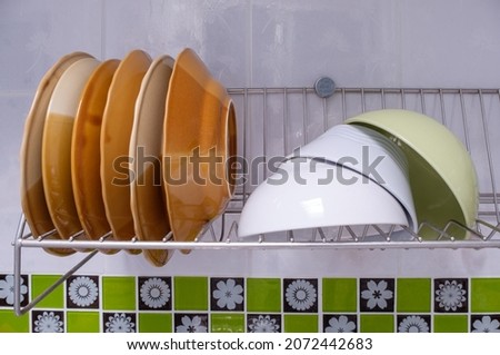 Closeup of the cleaned dish and blow are drying on the stainless dish drainer near the kitchen wall, front view for the copy space.