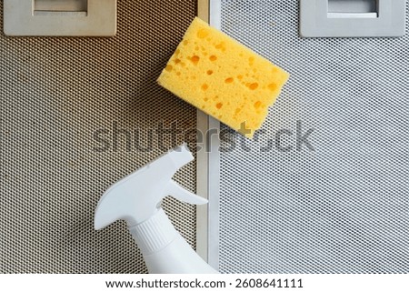Close-up of cleaning sponge and spray for the process of cleaning a dirty kitchen hood with foam. Modern cleaning and washing products.