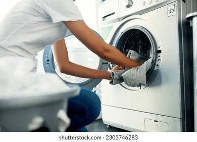 Closeup, cleaning and woman with laundry, machine and home with clothes, fabric and housekeeping. Zoom, female person and cleaner washing items, housework and laundromat with routine and service