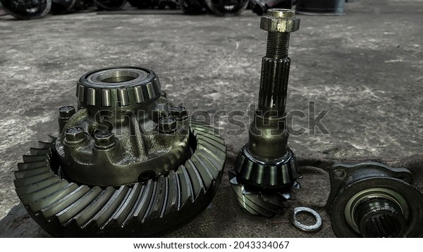 Close-up of the clear front, blurred back of truck\
rear differential and transmission parts, tools, maintenance, on\
the factory floor