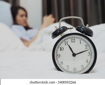 closeup of clock on the bed with women not sleep and playing smartphone in the concept of sleep late. - Shutterstock ID 1400592266