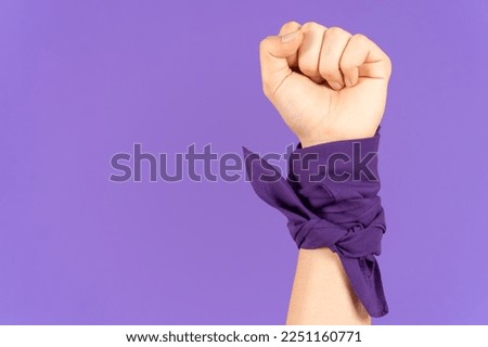 Closeup of closed fist and kerchief tied on wrist isolated on purple background. Feminism and protest concept with copy space Foto stock © 