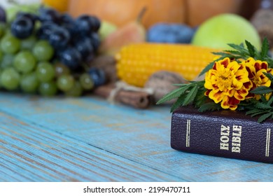 A Closeup Of A Closed Holy Bible Book With Flowers And Fresh Autumn Food In The Background. Thanksgiving Day, Christian Gratitude, Blessing, And Praise Concept.