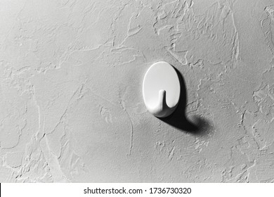Close-up of clothes hook on background of textured wall of grey.