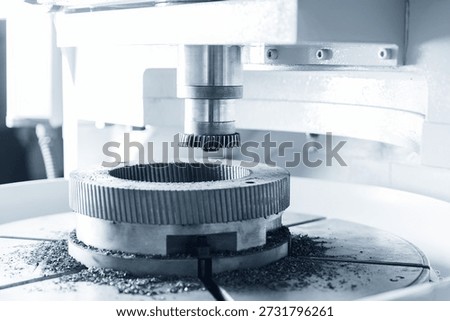 Close-up of cnc milling machine in operation with metal gear toothed.